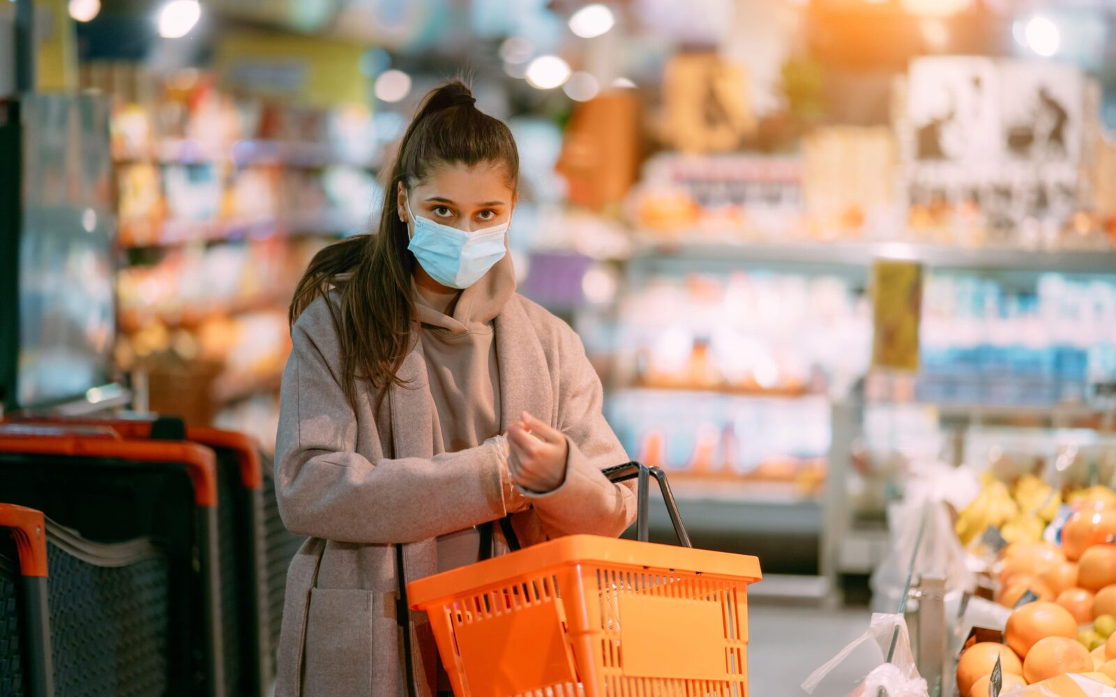 Oseba z nakupovalno košarico v živilski trgovini med bolniško odsotnostjo – simbol vprašanja, kaj je dovoljeno med bolniško po novih pravilih ZZZS.