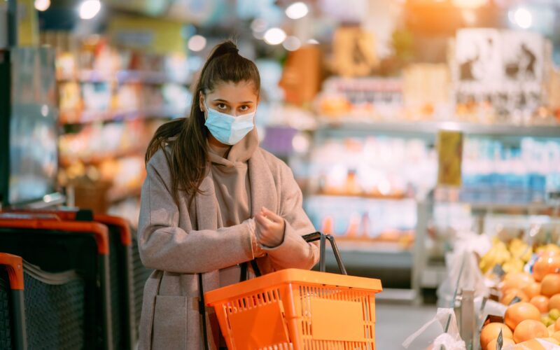 Oseba z nakupovalno košarico v živilski trgovini med bolniško odsotnostjo – simbol vprašanja, kaj je dovoljeno med bolniško po novih pravilih ZZZS.