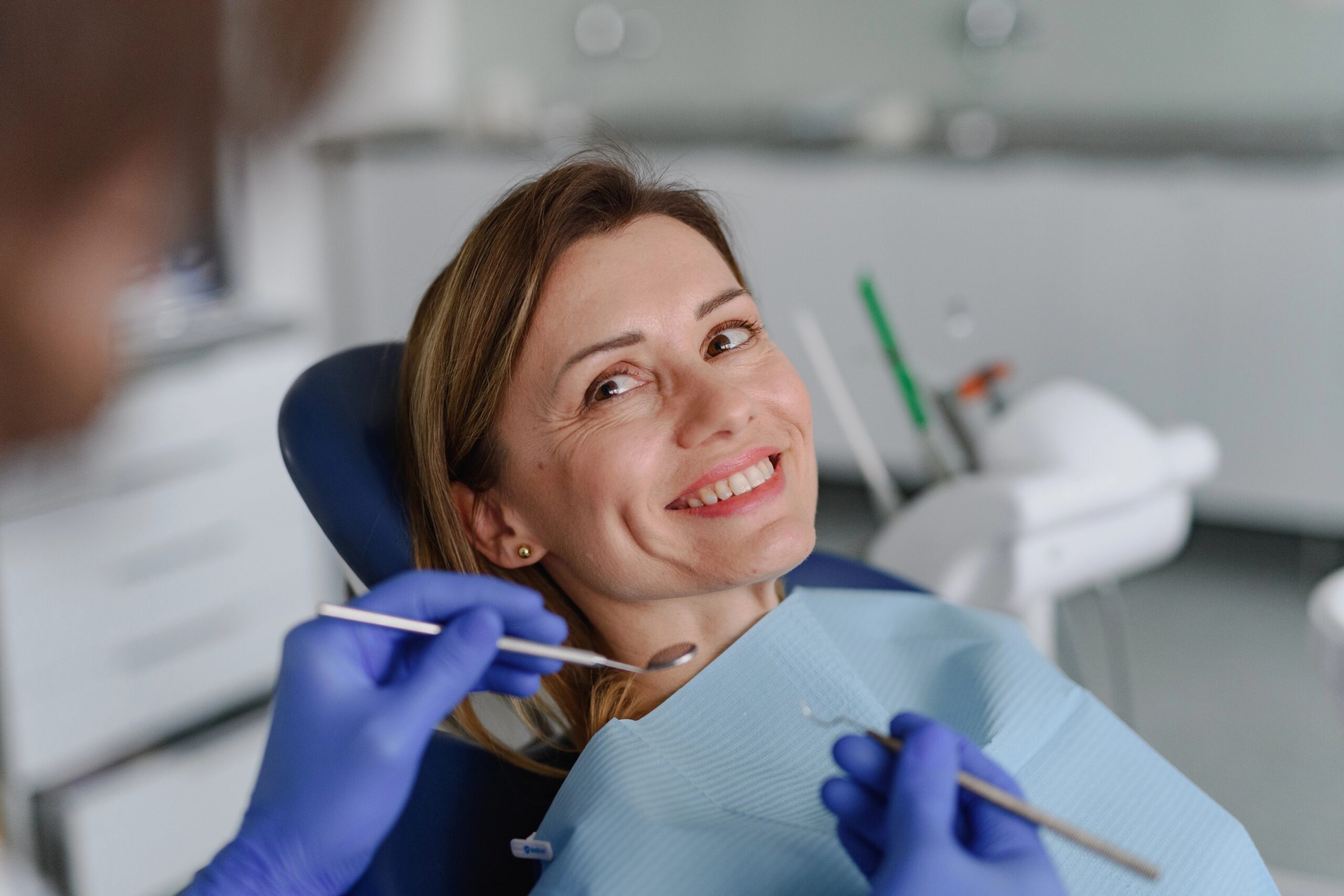 Mlada nasmejana ženska na rednem pregledu pri zobozdravniku - ključni korak pri skrbi za ustno zdravje