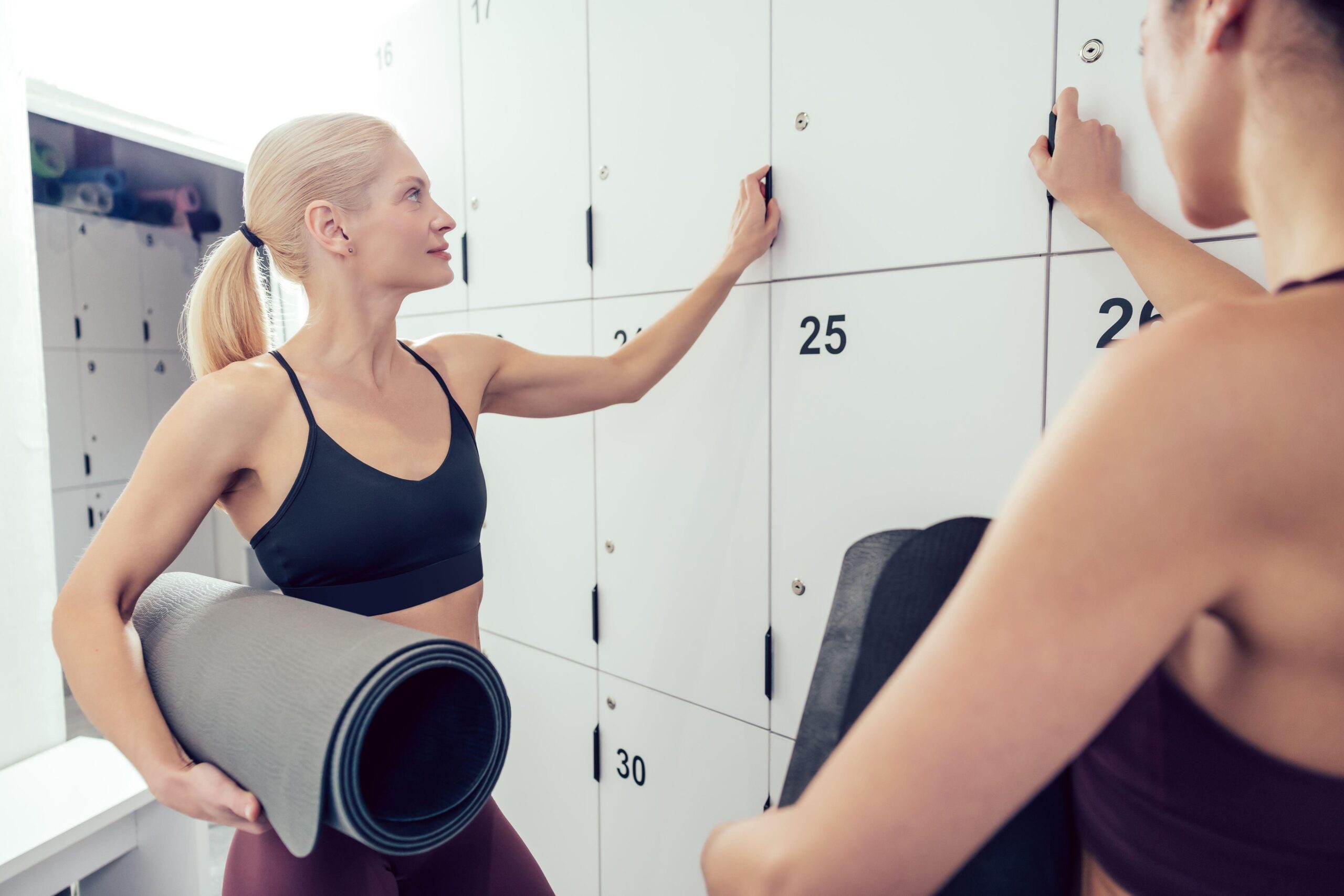 Dve mladi ženski se pogovarjata v fitnes garderobi