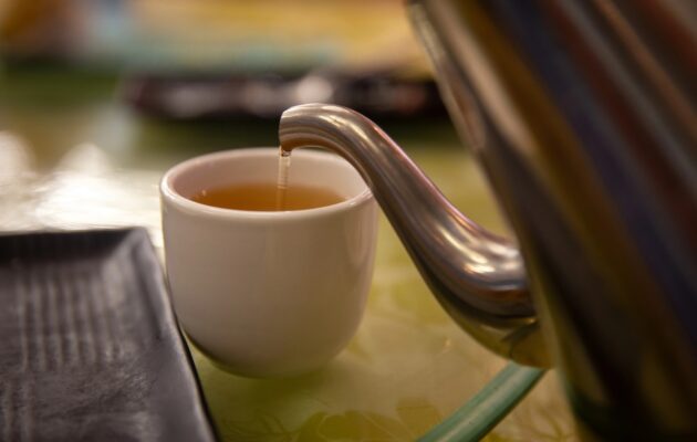 Natakanje čaja iz čajnika v belo skodelico