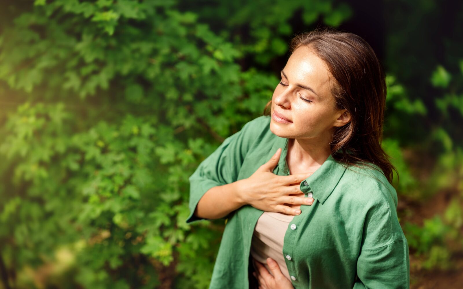 mlada odrasla ženska, ki v gozdu izvaja dihalne vaje
