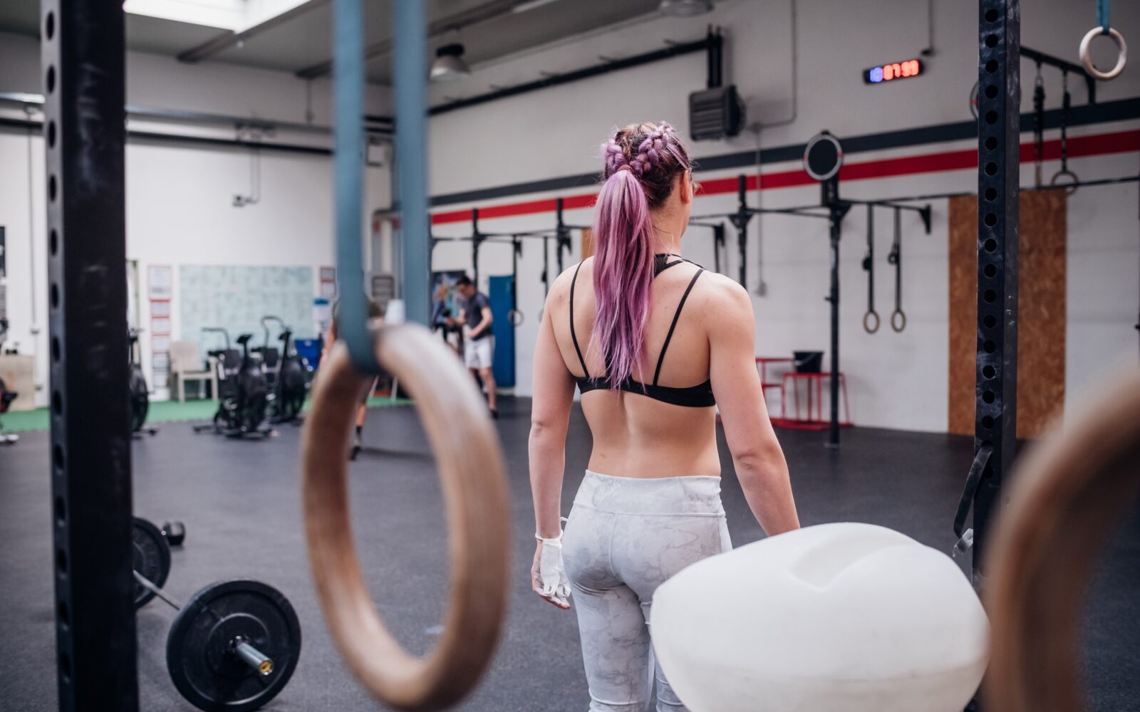 Mlada ženska stoji in vadi v fitnesu - kaj so ključni faktorji pri izbiri fitnesa