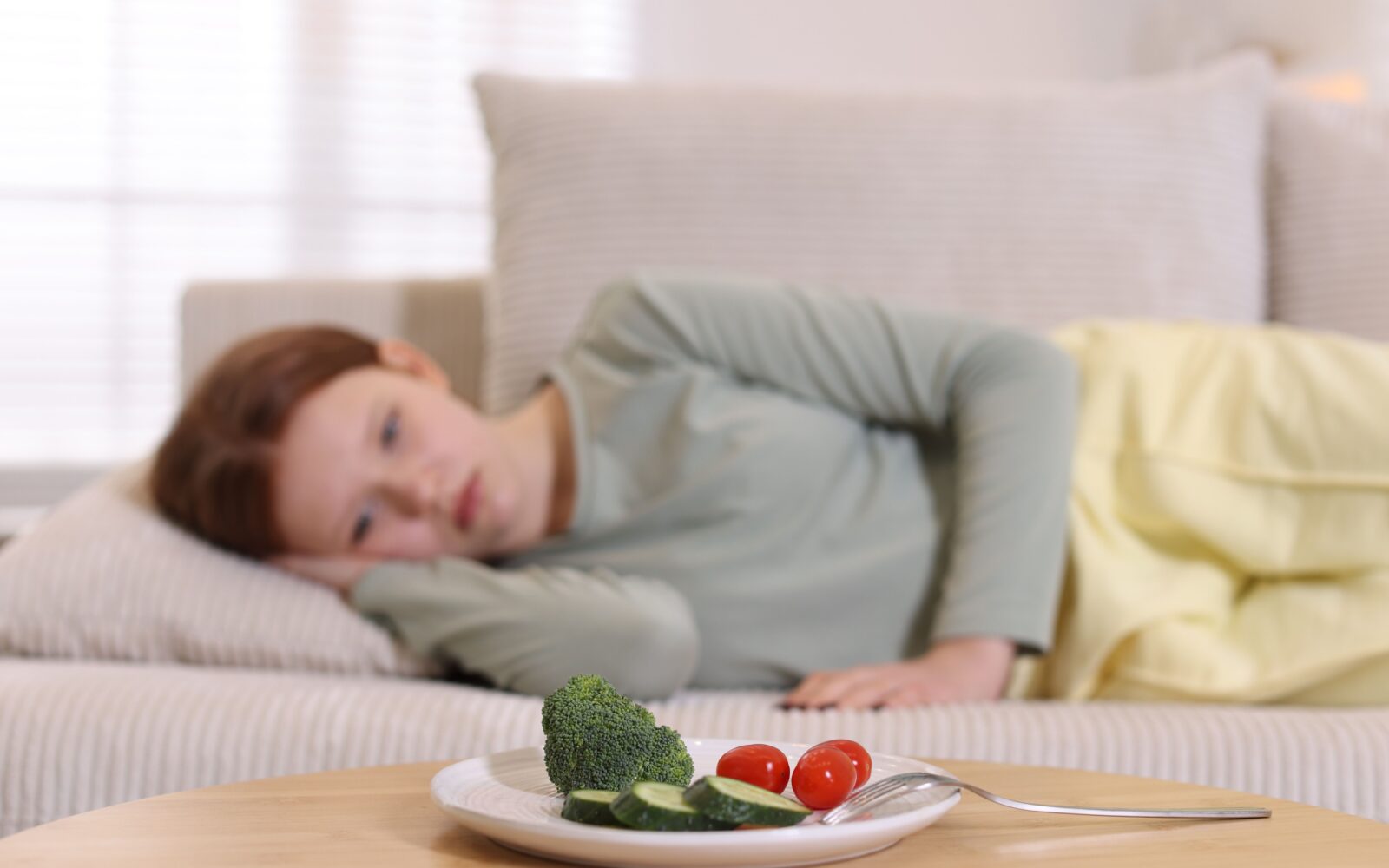 Deklica leži na kavču, na klubski mizici pred sabo ima krožnih s hrano, vendar noče jesti, ker ima motnjo hranjenja