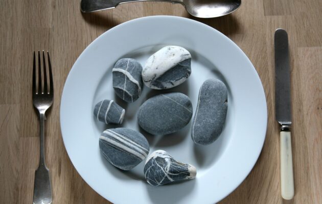 Krožnik s kamni kot simbol motnje pica, pri kateri ljudje uživajo neprehranske snovi