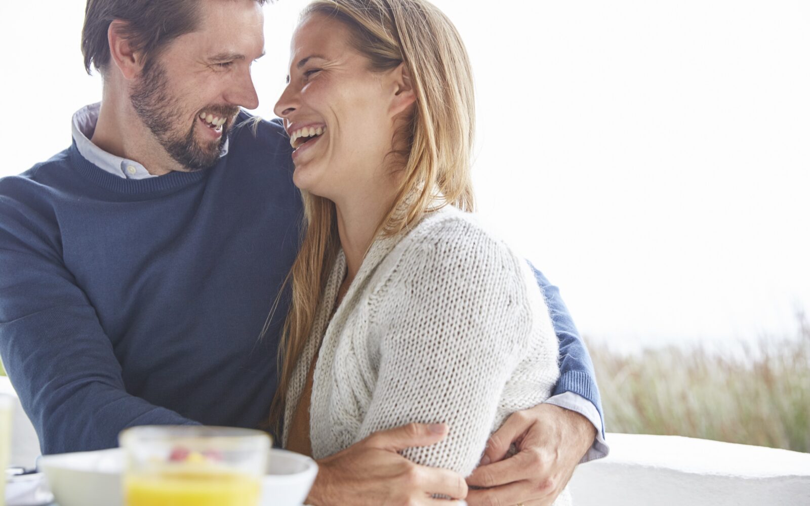 Vesel par se smeji in objem ob zajtrku