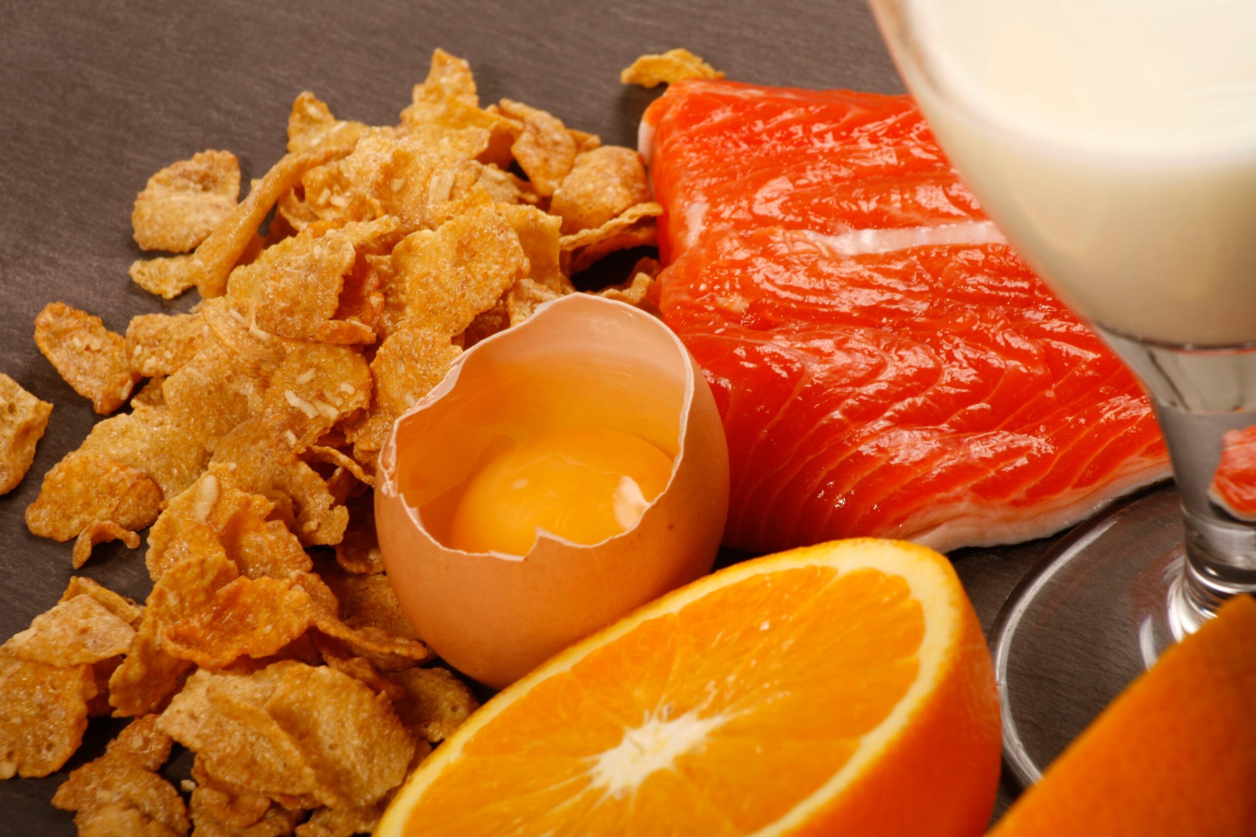 Na mizi so živlia, ki so bogati viri vitamina D - losos, mleko, pomaranča, jajca in kosmiči